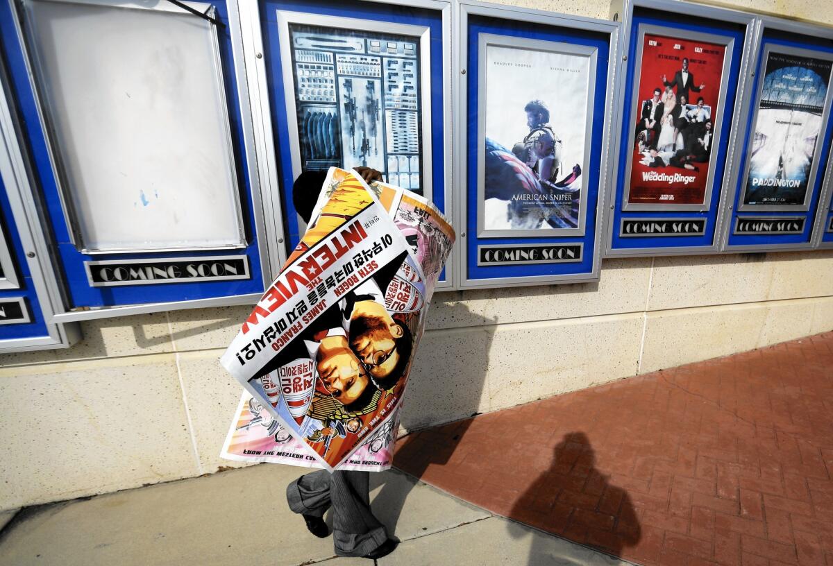 A poster for the movie "The Interview" is carried away by a worker after being pulled from a display case at a Carmike Cinemas movie theater in Atlanta on Wednesday.
