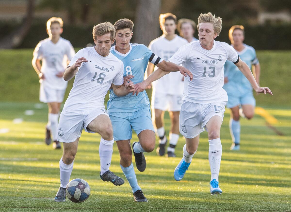 Newport Harbor's Tyler Kelly, left, and Jason Hayward, right, battle against Corona del Mar's Aidan Holmes, center, during a Battle of the Bay match at Bonita Creek Park on Friday.