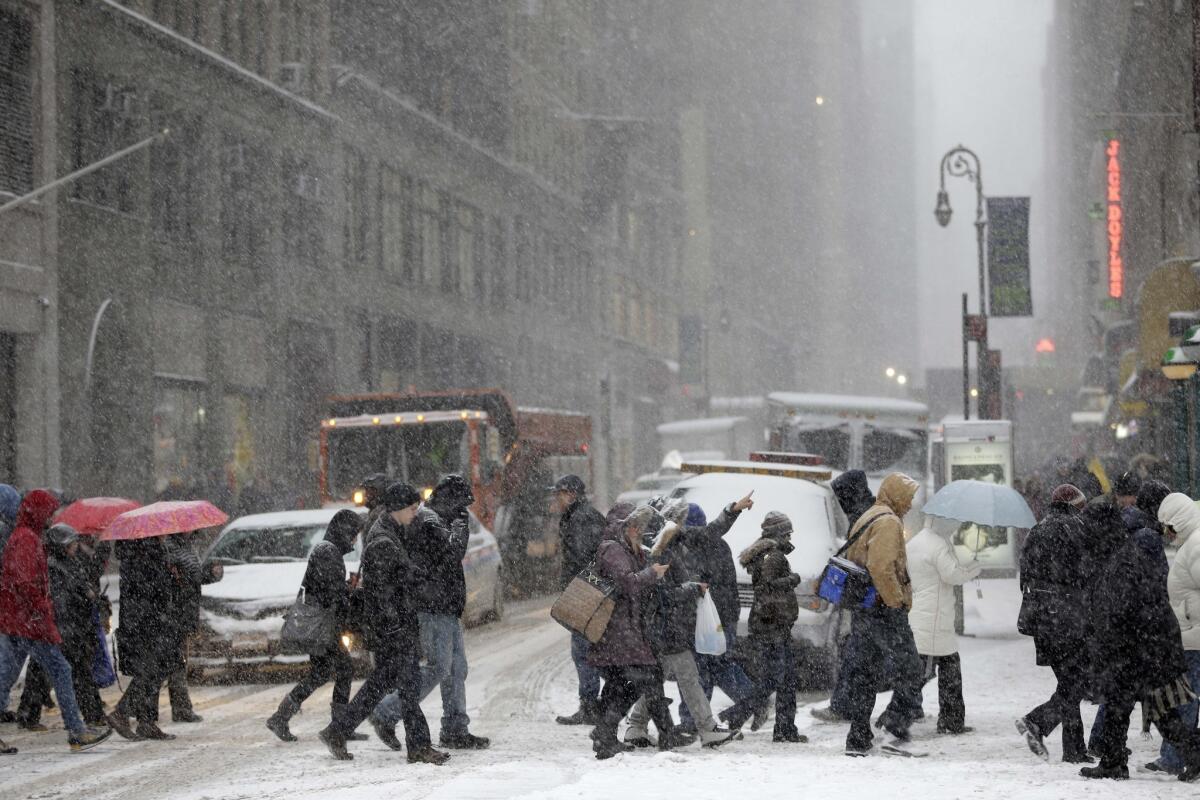 Pedestrians walk through heavy snow in the midtown section of New York.
