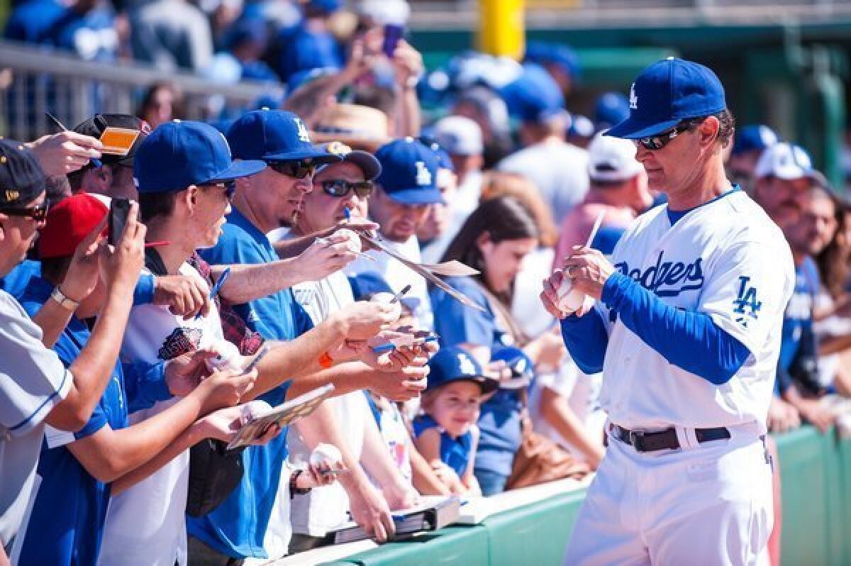 Dodgers Manager Don Mattingly signs autographs before the spring training opener Saturday against the Chicago White Sox at Camelback Ranch.