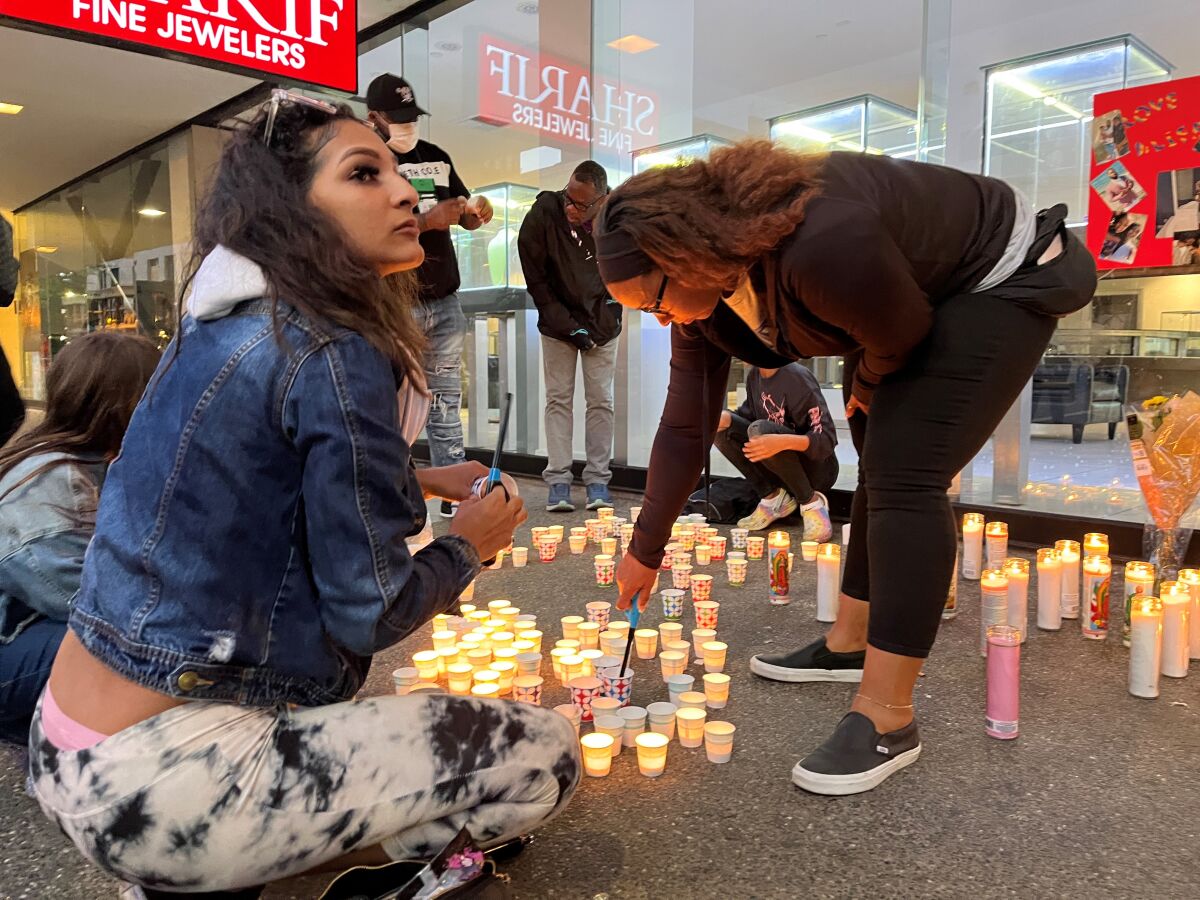 Two women light candles at a vigil.