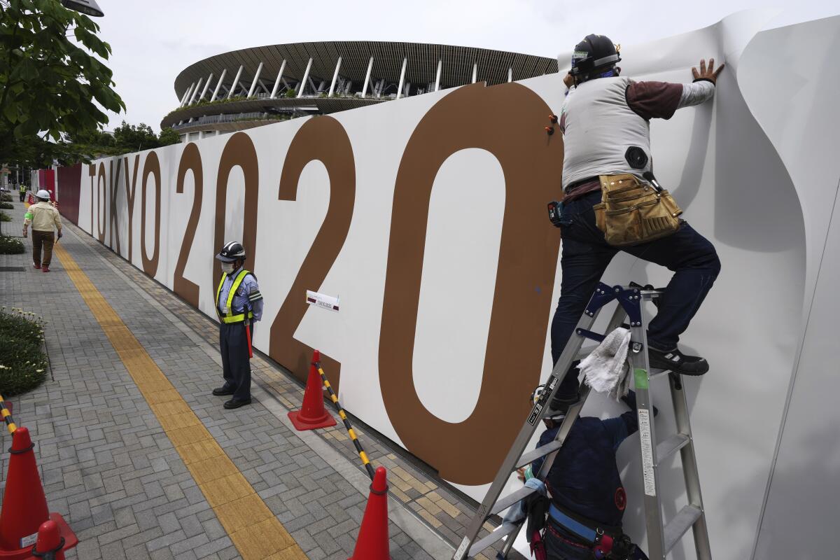 Obreros colocan logos en una barrera frente al Estadio Nacional