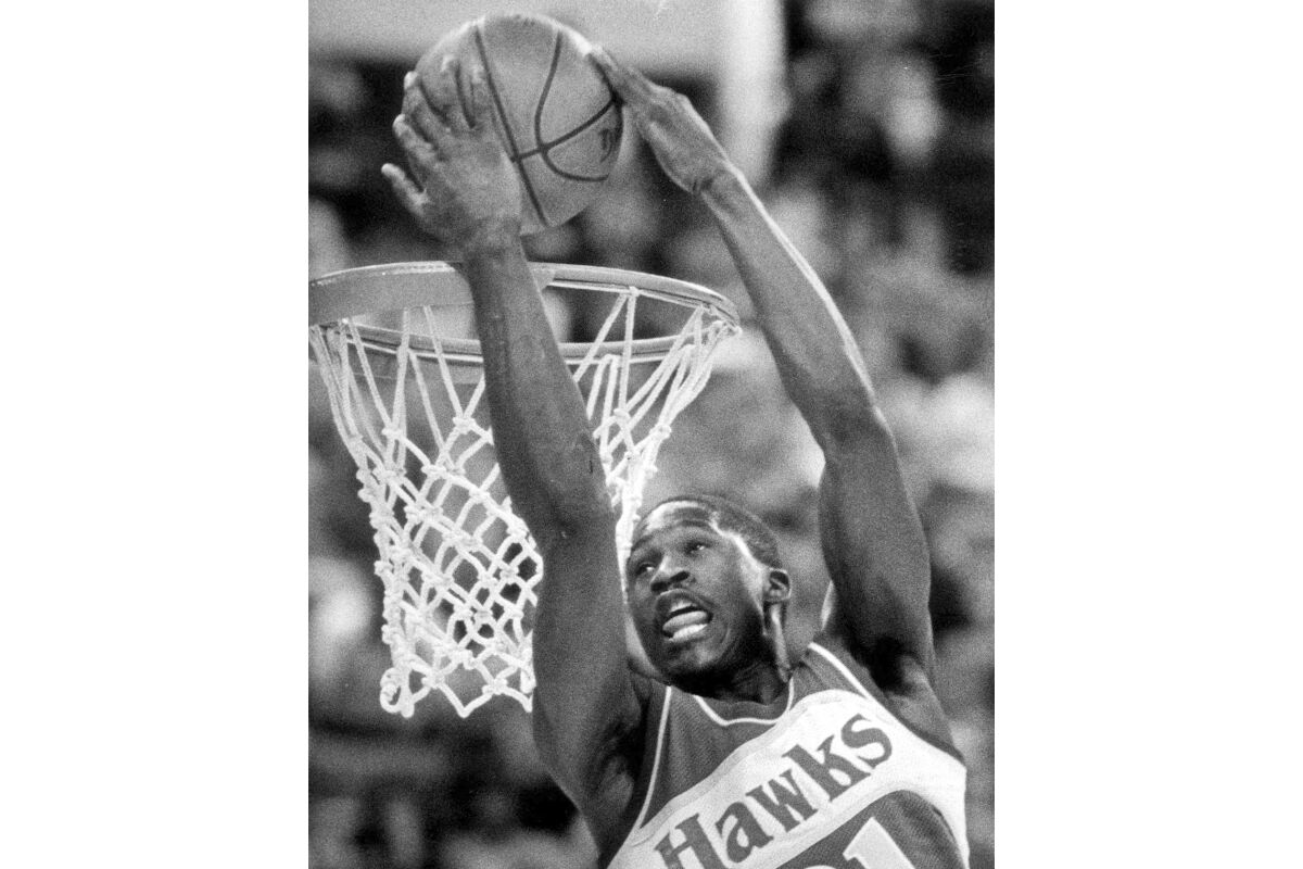FILE - Atlanta Hawks forward Dominique Wilkins dunks the ball over his head during the NBA Slam Dunk Contest in Indianapolis on Feb. 9, 1985. Wilkins beat rookie Michael Jordan, of the Chicago Bulls, in an epic Slam Dunk Contest. (AP Photo/Doug Atkins, File)