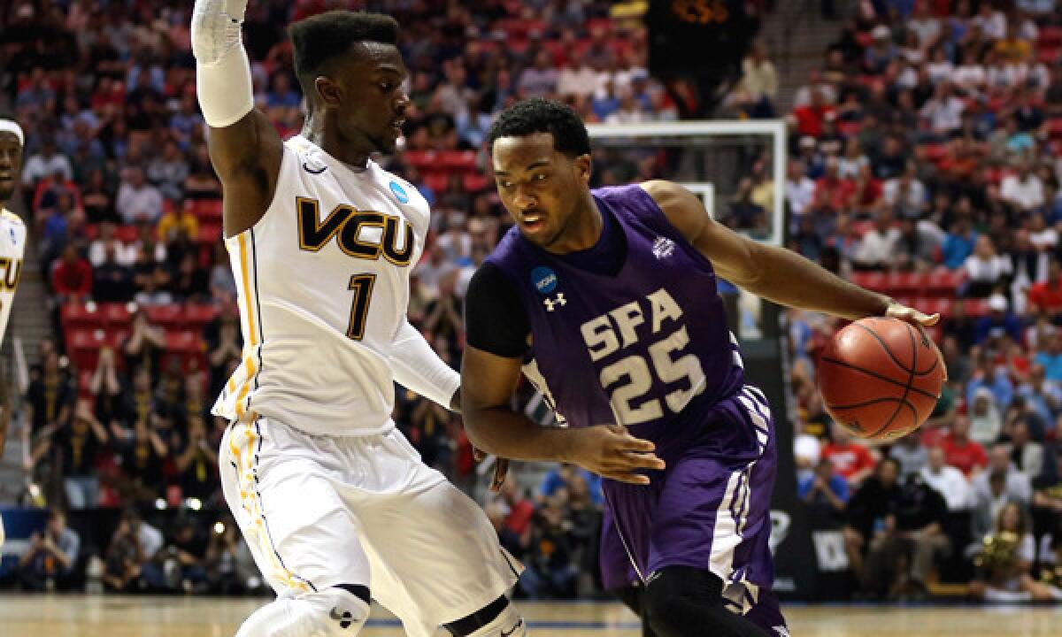 Stephen F. Austin's Desmond Haymon, right, drives around Virginia Commonwealth's JeQuan Lewis during the Lumberjacks' 77-75 overtime win in the second round of the NCAA tournament on Friday.