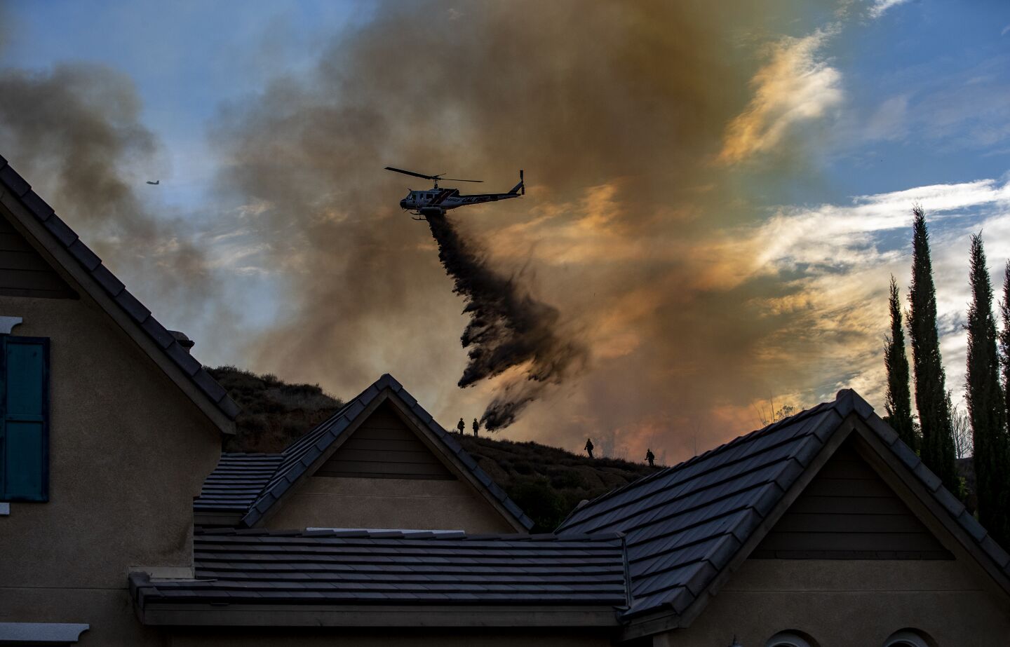 A Cal Fire helicopter makes a water crop on the Skyline fire behind homes on Clearing Lane in Corona.