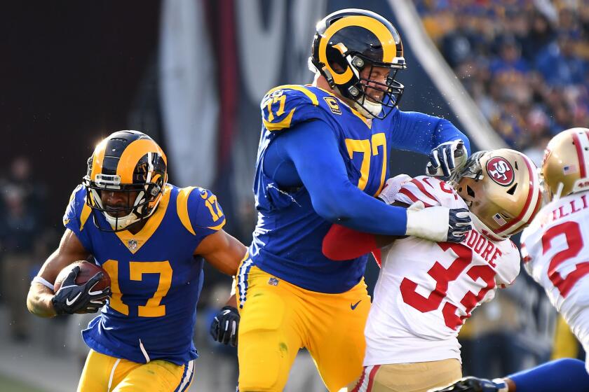 Rams tackle Andrew Whitworth provides a block for receiver Robert Woods as 49ers Tarvarius Moore is pushed back.