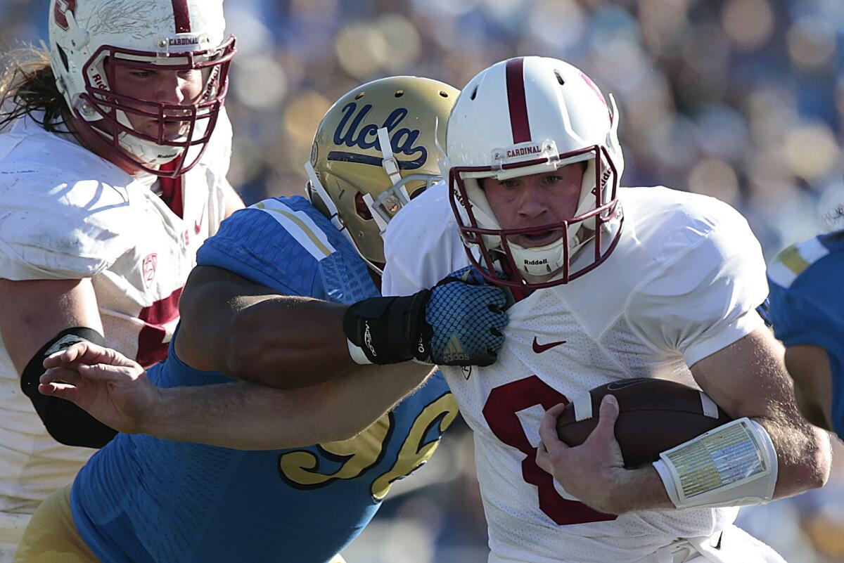 Stanford quarterback Kevin Hogan wiggles out of the grasp of UCLA defensive lineman Eli Ankou late in the first half of the Bruins' 31-10 loss to the Cardinal on Nov. 28.