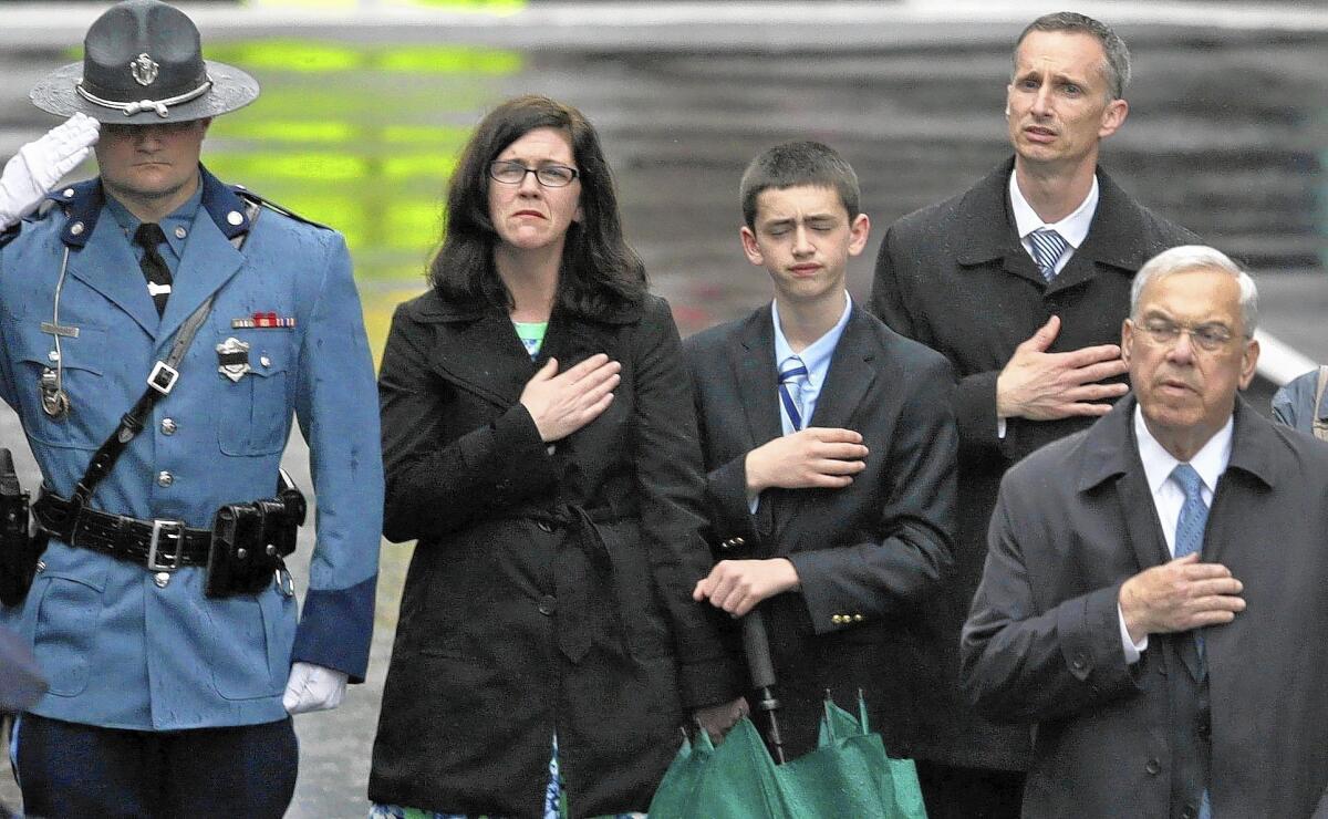 The family of 8-year-old bombing victim Martin Richard - mother Denise, brother Henry and father Bill - stand with former Mayor Thomas Menino, right, during a tribute ceremony on the one-year anniversary of the Boston Marathon bombings.