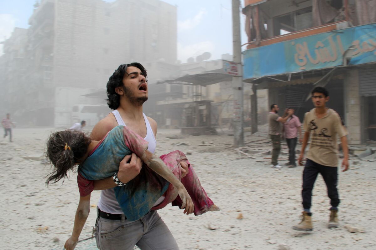 A man carries a young girl who was injured in a reported barrel-bomb attack  in Aleppo, Syria. 