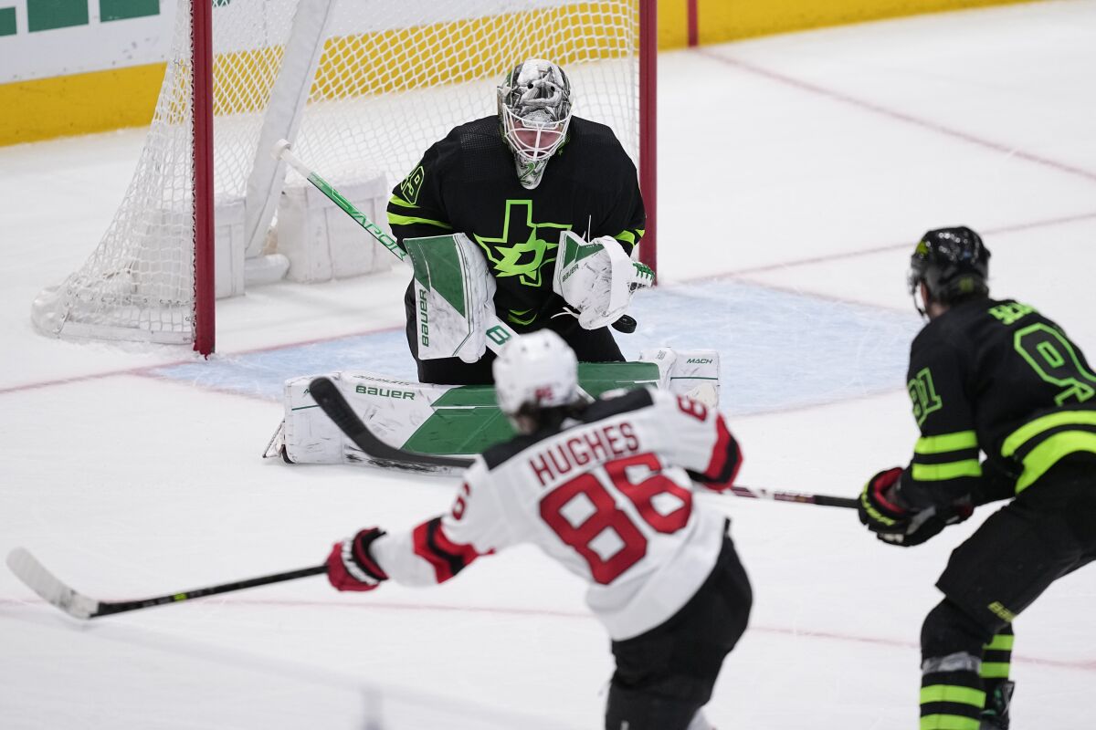Dallas Stars goaltender Jake Oettinger (29) is unable to stop a a shot by New Jersey Devils' Jack Hughes (86) that scored as Tyler Seguin (91) looks on during overtime an NHL hockey game, Friday, Jan. 27, 2023, in Dallas. The Devils won 3-2. (AP Photo/Tony Gutierrez)
