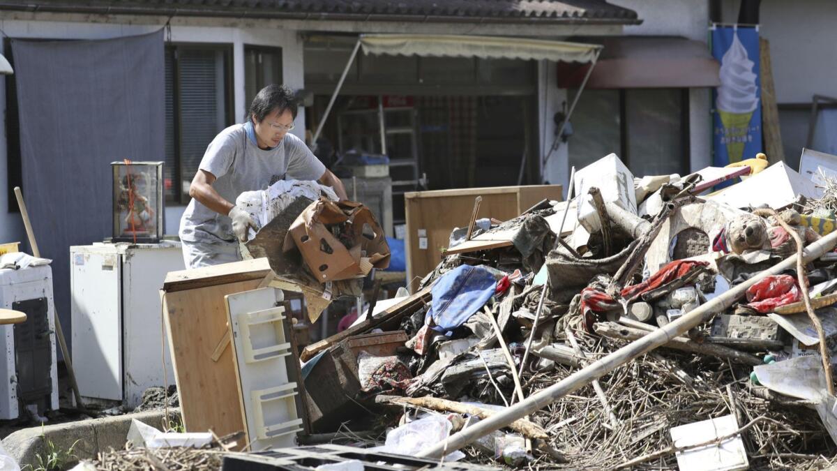 A man clears debris caused by a heavy rain in Soja, Japan.