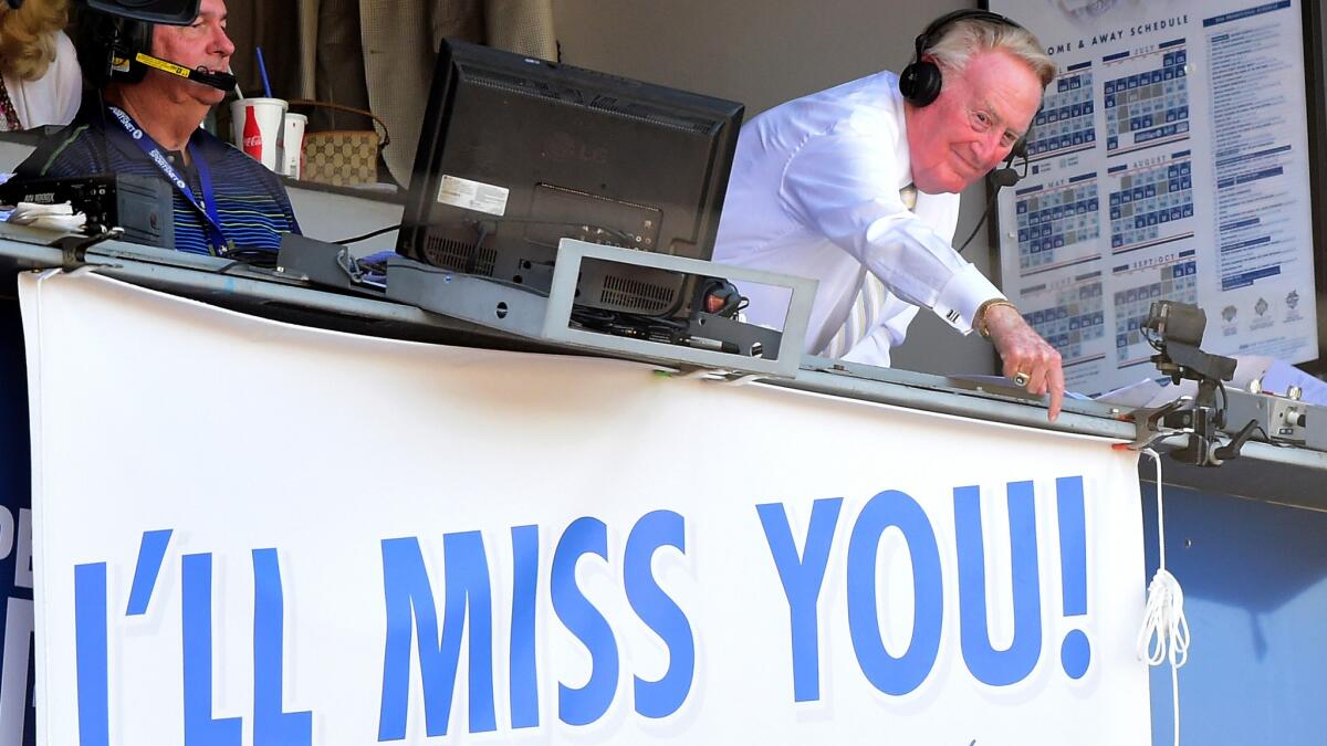 Vin Scully points to his sign letting the Dodger Stadium crowd know how he feels during his final broadcast from Dodger Stadium.