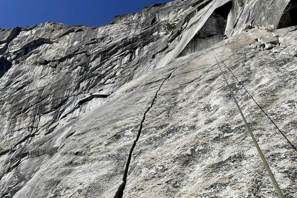 A long crack runs up the face of a granite rock formation, seen from below