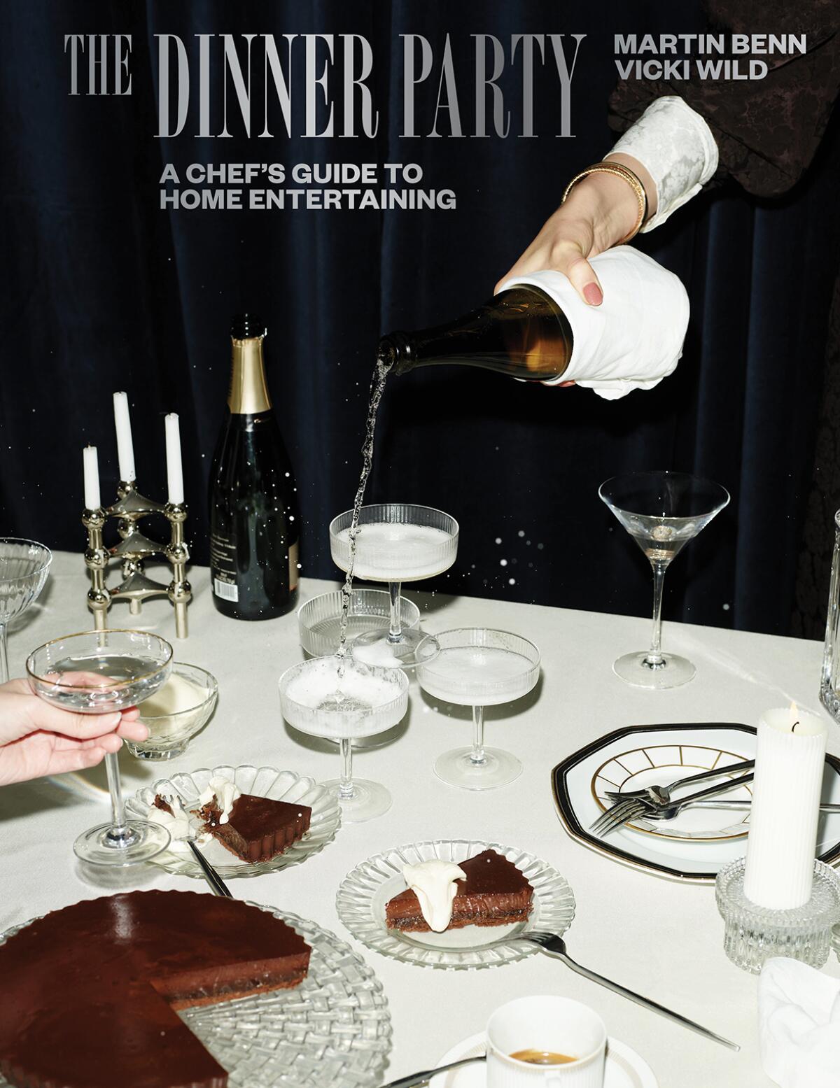 The cover of "The Dinner Party" cookbook: A hand from off camera pours champagne next to a chocolate cake