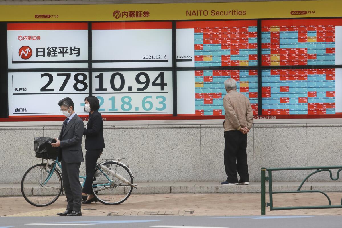 A man looks at an electronic stock board of a securities firm in Tokyo, Monday, Dec. 6, 2021 . Shares were mixed in Asia on Monday after troubled Chinese property developer Evergrande warned late Friday it may run out of money. (AP Photo/Koji Sasahara)