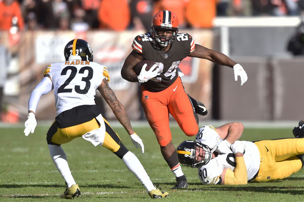 Cleveland Browns running back Nick Chubb (24) breaks away from a tackle by Pittsburgh Steelers outside linebacker T.J. Watt (90) during the second half of an NFL football game, Sunday, Oct. 31, 2021, in Cleveland. (AP Photo/David Richard)