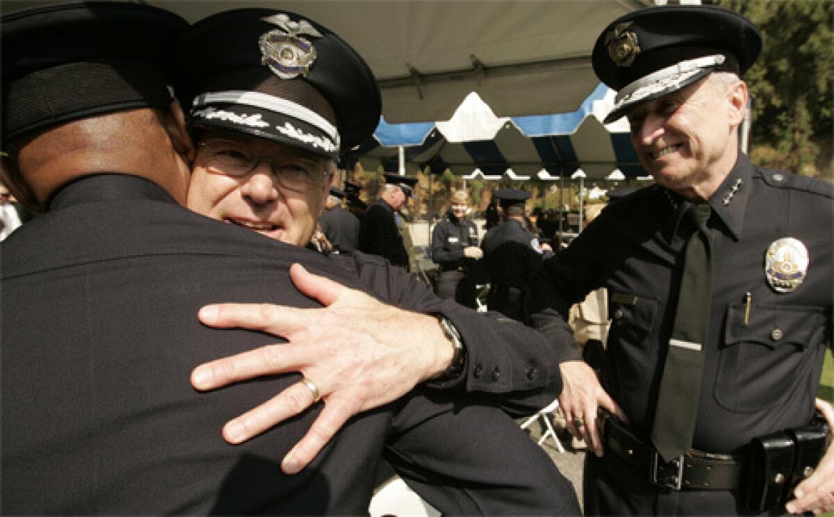 STEPPING DOWN: LAPD Deputy Chief Gary Brennan, center, gets a hug from a colleague as Chief William J. Bratton looks on during graduation ceremonies Friday at the Police Academy.