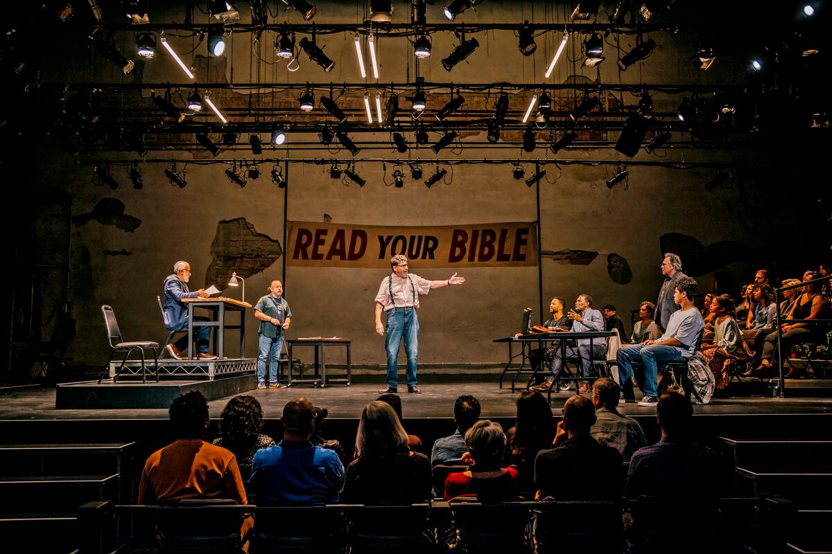 Actors ona stage under a "Read Your Bible" banner, with audience members in front of and to the side of them.
