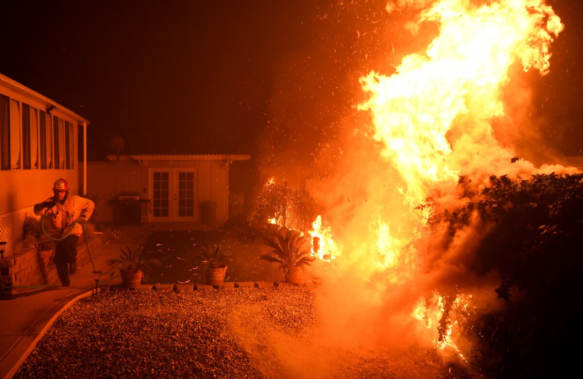 A firefighter runs as the heat form a shrub is too much as the Thomas Fire reaches the town of La Conchita.