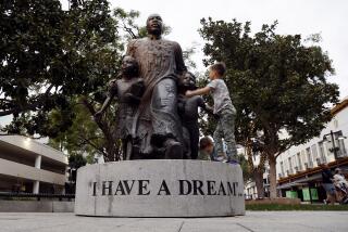 RIVERSIDE, CA - JANUARY 16, 2022: Youngsters climb on the pedestal of the Martin Luther King "I Have a Dream" statue in the Pedestrian Mall on the eve before Martin Luther King day on January 16, 2022 in Riverside, California.(Gina Ferazzi / Los Angeles Times)