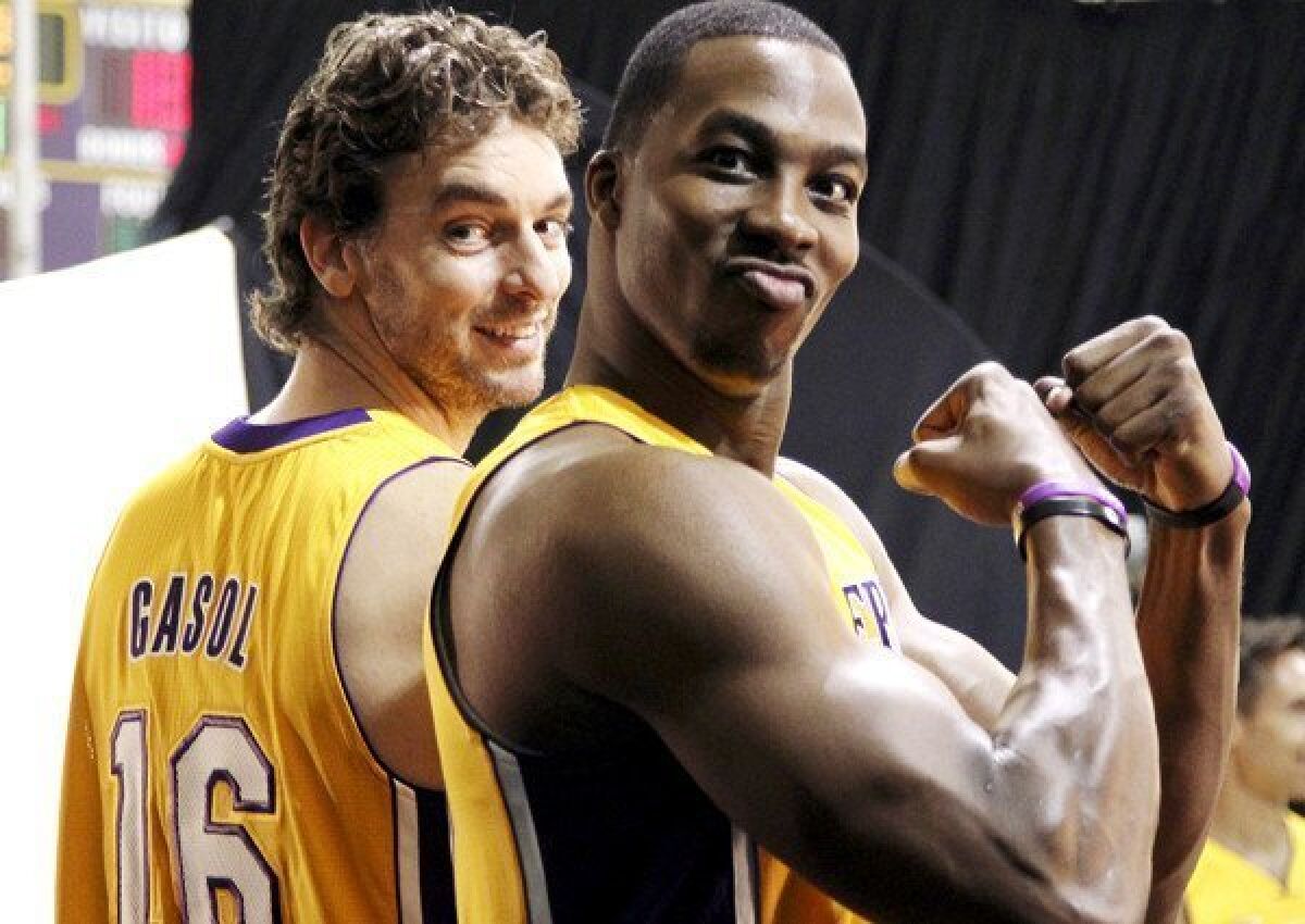 Dwight Howard flexes as he and Pau Gasol wait to take photographs during media day.