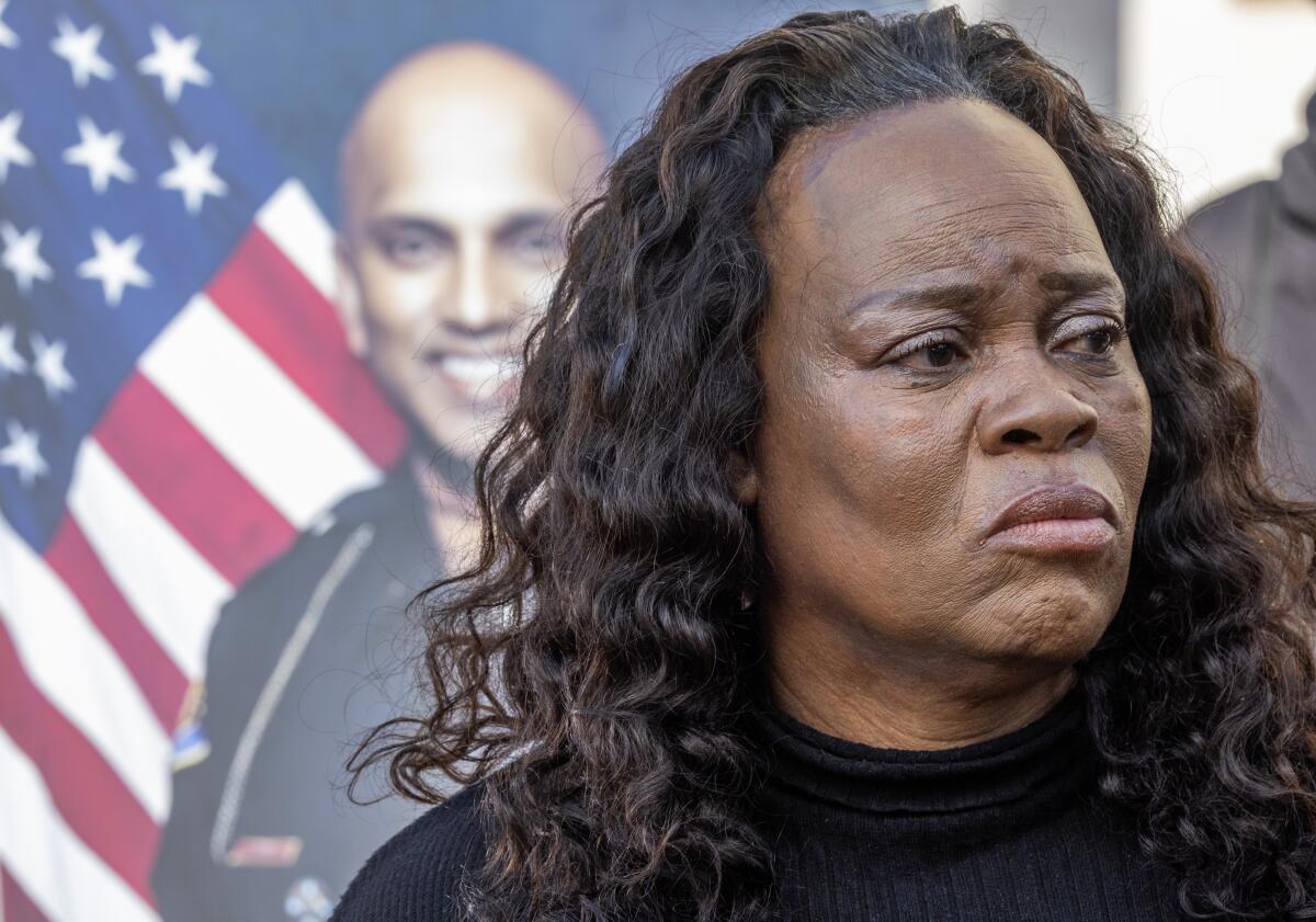 A woman stands in front of a photo of a police officer and the U.S. flag