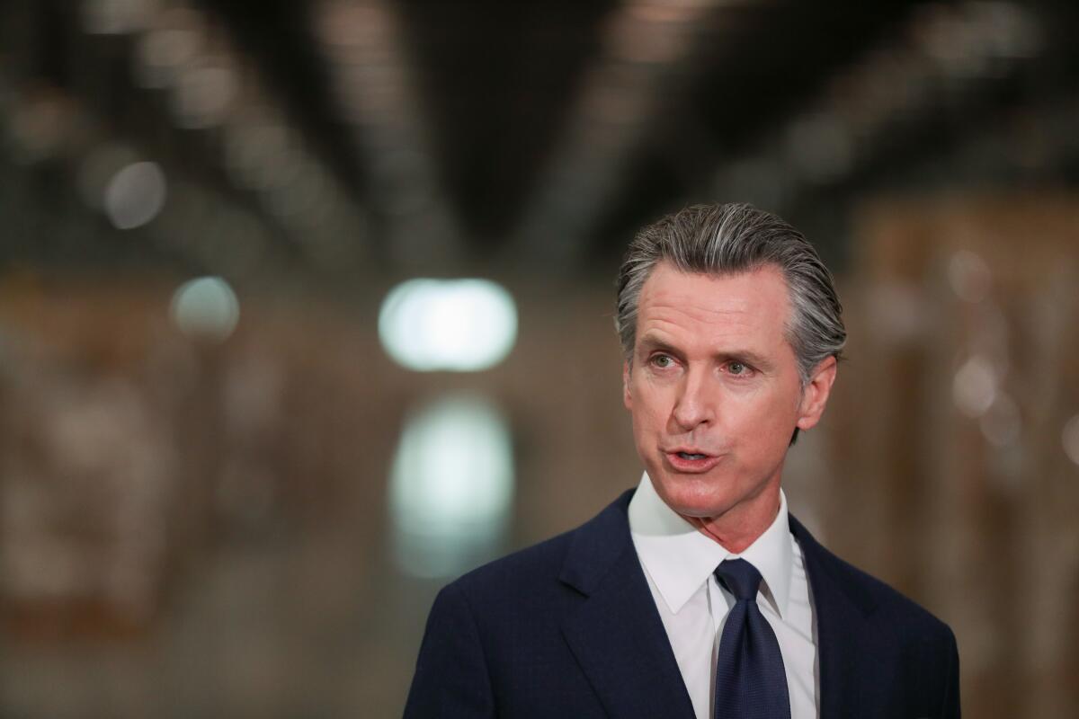 Gov. Gavin Newsom in a dark suit and tie, speaking 