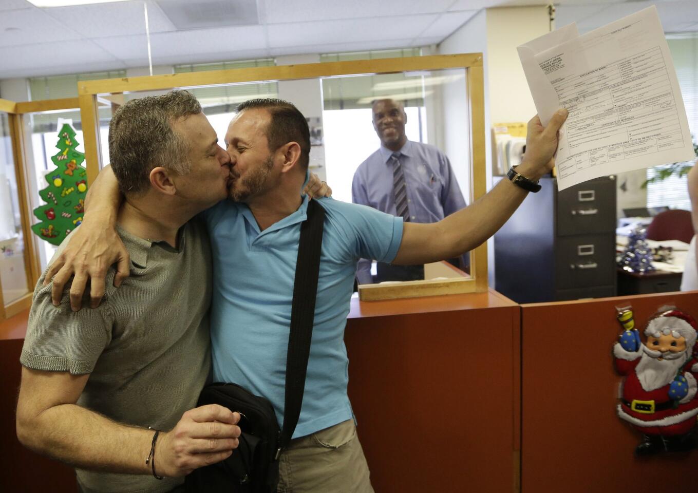 Jeff Ronci, left, kisses his partner of 15 years, Juan Talavera, as they hold up their marriage license at the Miami-Dade County clerk of courts office.