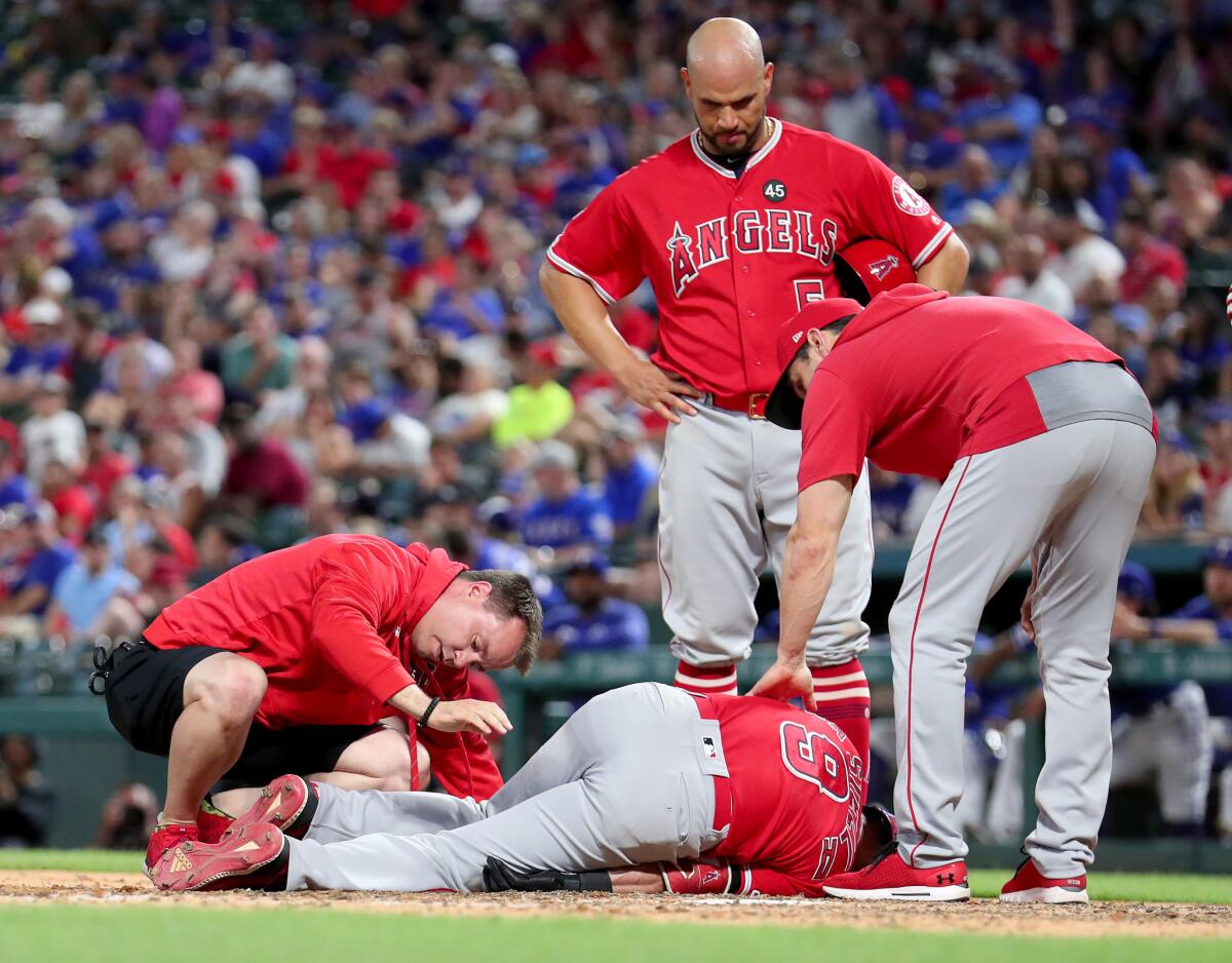Angels team personnel assist Tommy La Stella (9) after he was injured while at bat against the Texas Rangers in the top of the sixth inning on Tuesday in Arlington, Texas.