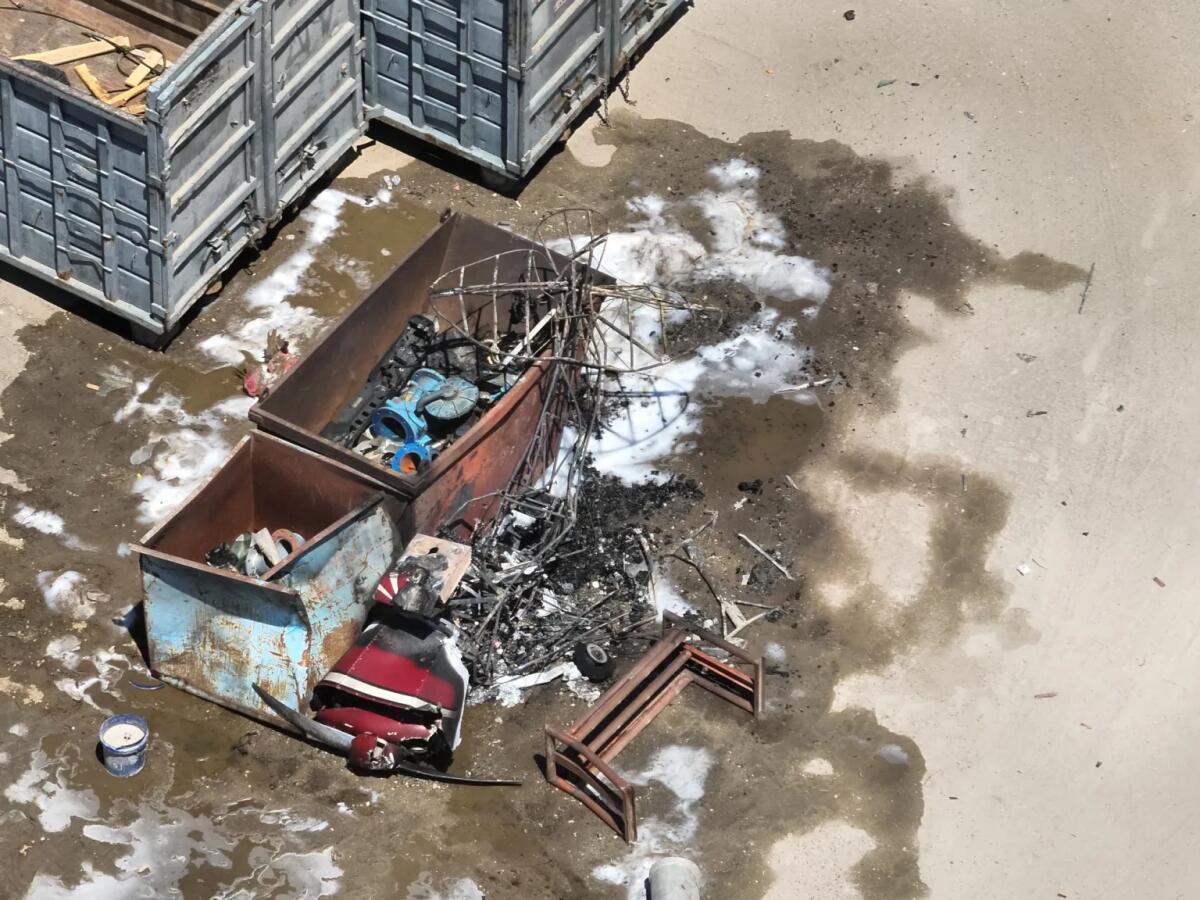 Wreckage is seen on the ground near trash containers.