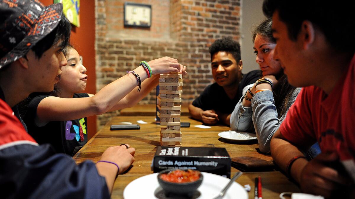 A group of young people play Tumbling Tower at the GameHaus Cafe in Glendale.