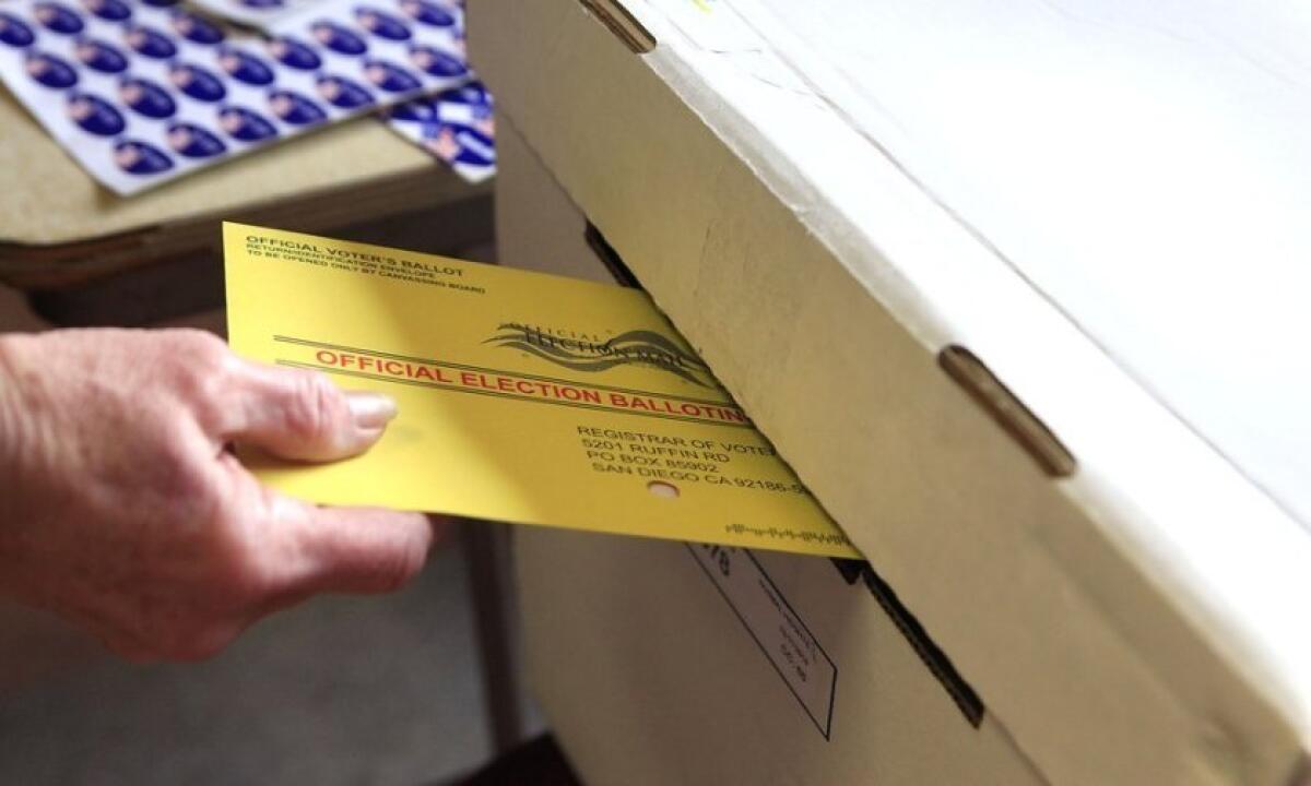 A poll worker places a ballot in a voting box.