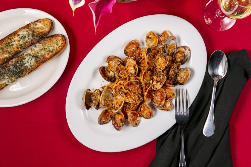 An overhead photo of spaghetti and clams with a side of garlic bread.