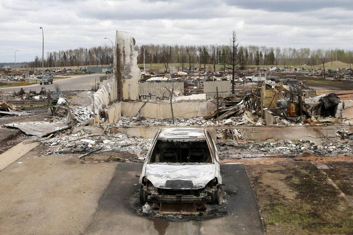 A wildfire-charred vehicle and home are pictured in the Beacon Hill neighborhood of Fort McMurray, Canada, on May 9.