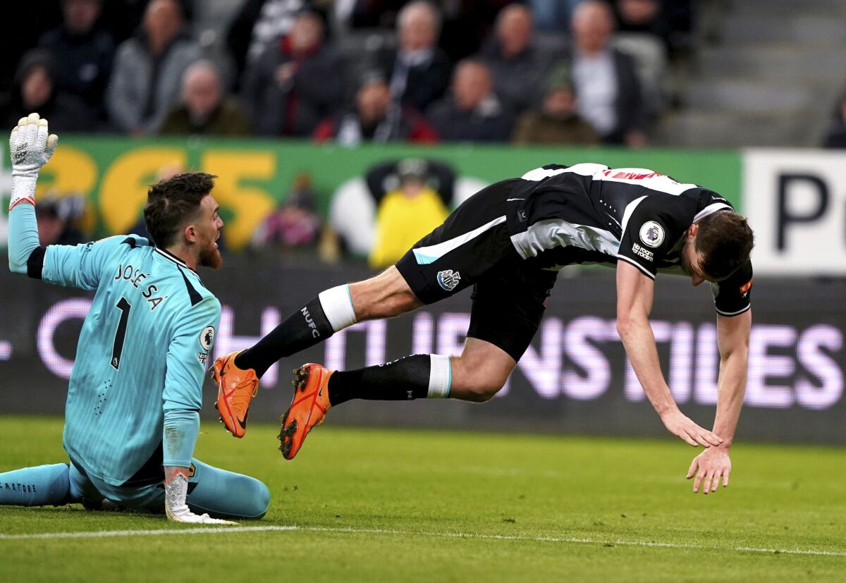 Wolverhampton Wanderers goalkeeper Jose Sa, left, fouls Newcastle United's Chris Wood resulting in a penalty during their English Premier League soccer match at St James' Park, Newcastle, England, Friday, April 8, 2022. (Owen Humphreys/PA via AP)