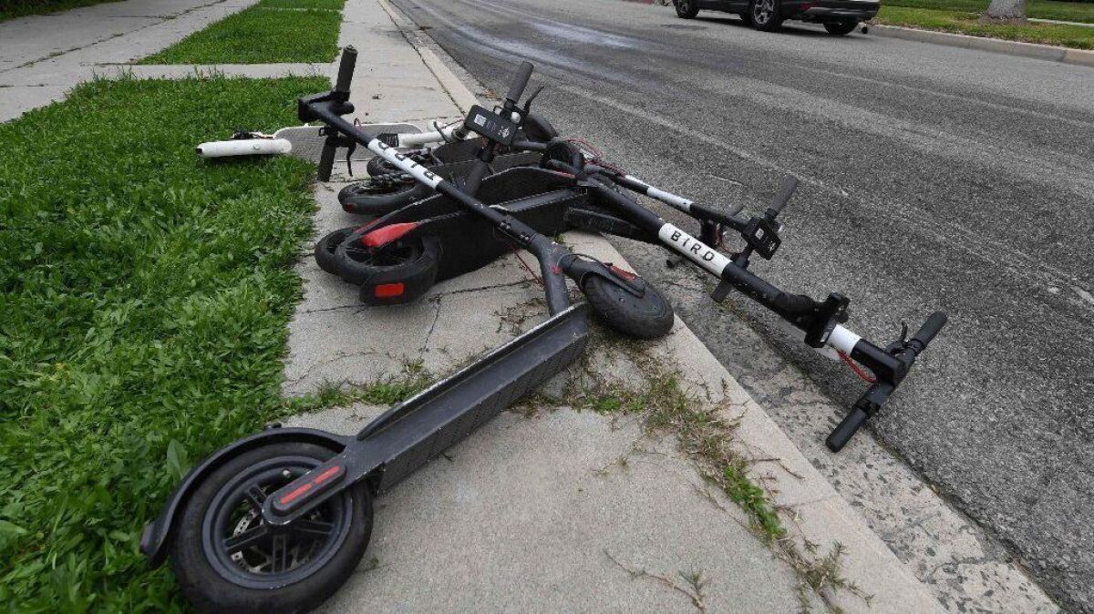 Electric scooters lie on a sidewalk in Los Angeles on Feb. 13.