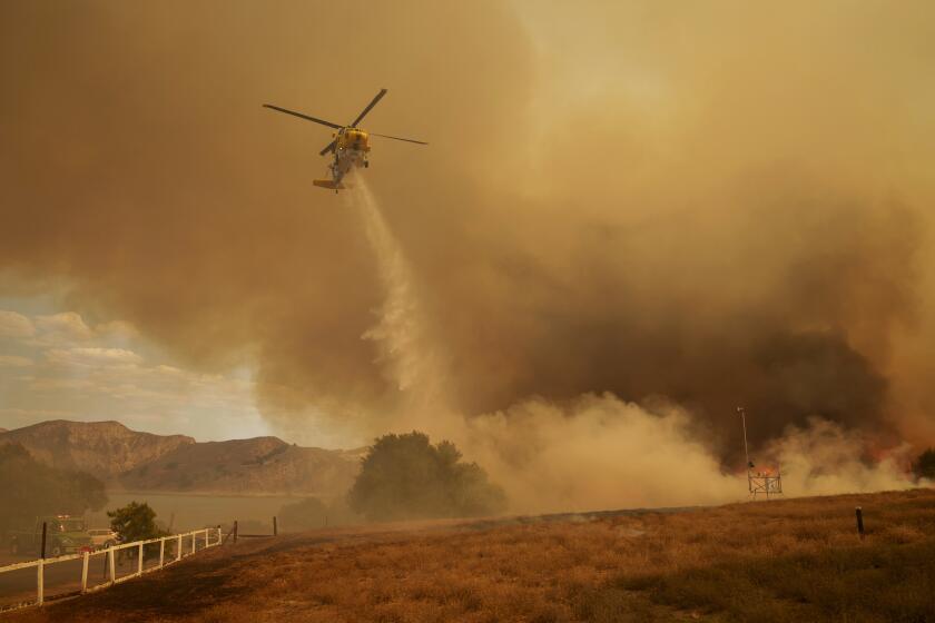 A fire department helicopter drops water on the advancing Felicia fire in Piru, Calif., Thursday, Oct. 3, 2024. (AP Photo/Eric Thayer)