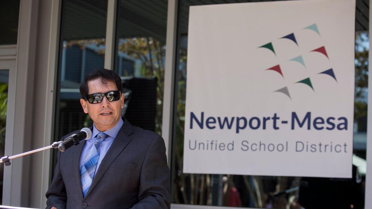 Fred Navarro speaks during a time capsule burial event at the Newport-Mesa Unified School District offices on June 2. The new logo is behind him.