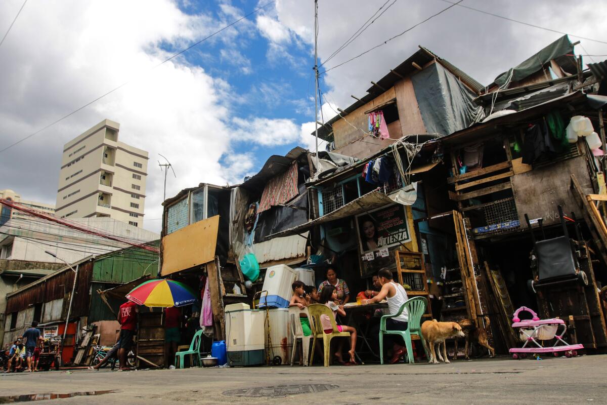 Jacquelin Marsan and her family of eight children eat dinner outside their home in a Manilla in a neighborhood called Del Pan Binondo.