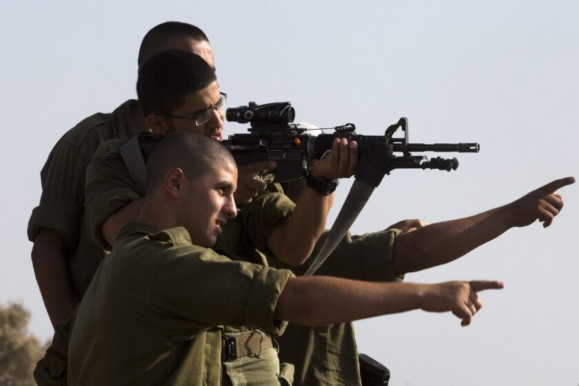 Israeli soldiers, one using the scope on his assault rifle, look toward the Gaza Strip the Israeli town of Sderot on Monday.