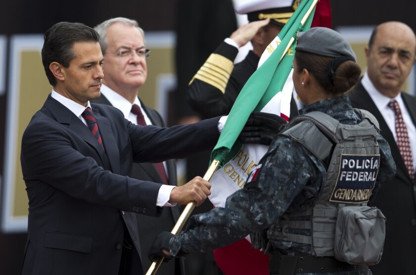 Mexico's President Enrique Pena Nieto delivers a Mexican flag to an officer of the nation's newest police force, known as the gendarmerie, during the launching ceremony Friday for the new force at the Federal Police headquarters in Mexico City.