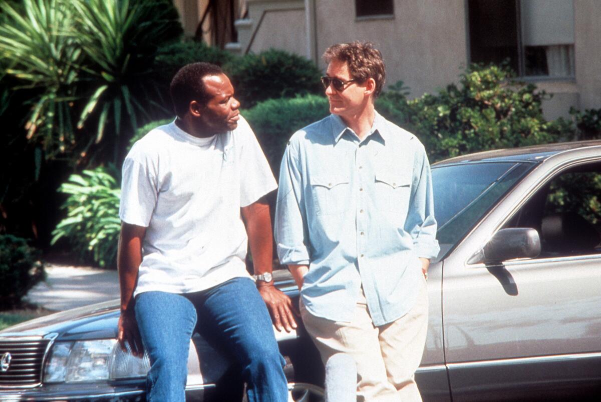 Two men sit on the front side of a car.