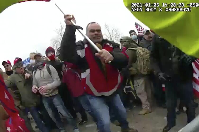 FILE - This still frame from Metropolitan Police Department body worn camera video shows Thomas Webster, in red jacket, at a barricade line at on the west front of the U.S. Capitol on Jan. 6, 2021, in Washington. Retired New York City police officer Webster is the next to go on trial, with jury selection scheduled to begin Monday, April 25, 2022. Webster has claimed he was acting in self-defense when he tackled a police officer who was trying to protect the Capitol from a mob on Jan. 6. (Metropolitan Police Department via AP, File)