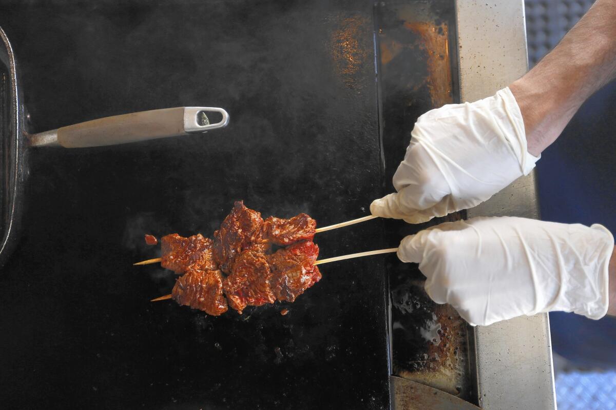 Adiel Nahmias grills up some meat at The Holy Grill. Nahmias, 30, is the food truck's co-owner and chef.