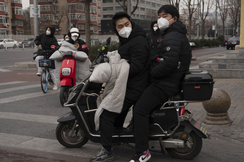 Residents wearing masks cross an intersection in Beijing, Friday, Dec. 2, 2022. More cities eased restrictions, allowing shopping malls, supermarkets and other businesses to reopen following protests last weekend in Shanghai and other areas in which some crowds called for President Xi Jinping to resign. (AP Photo/Ng Han Guan)