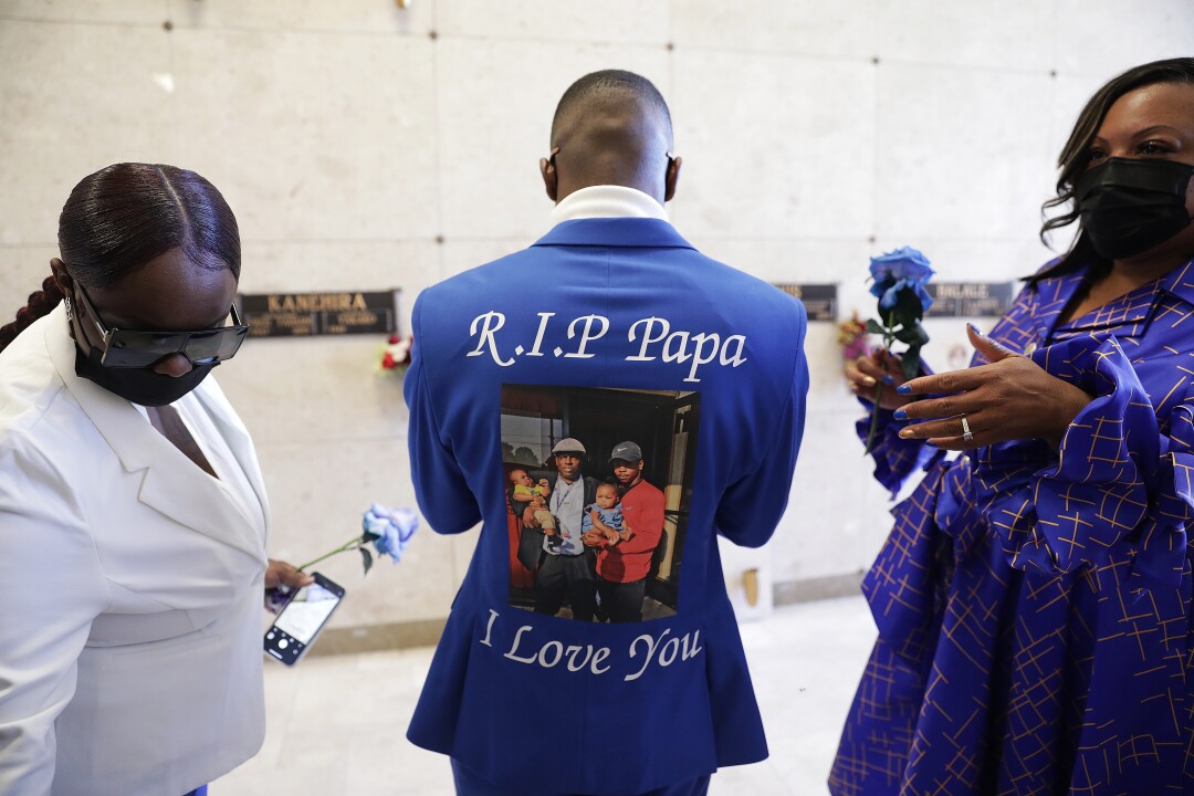 A man wears a blue suit that says "RIP Papa, I Love You" with a photo