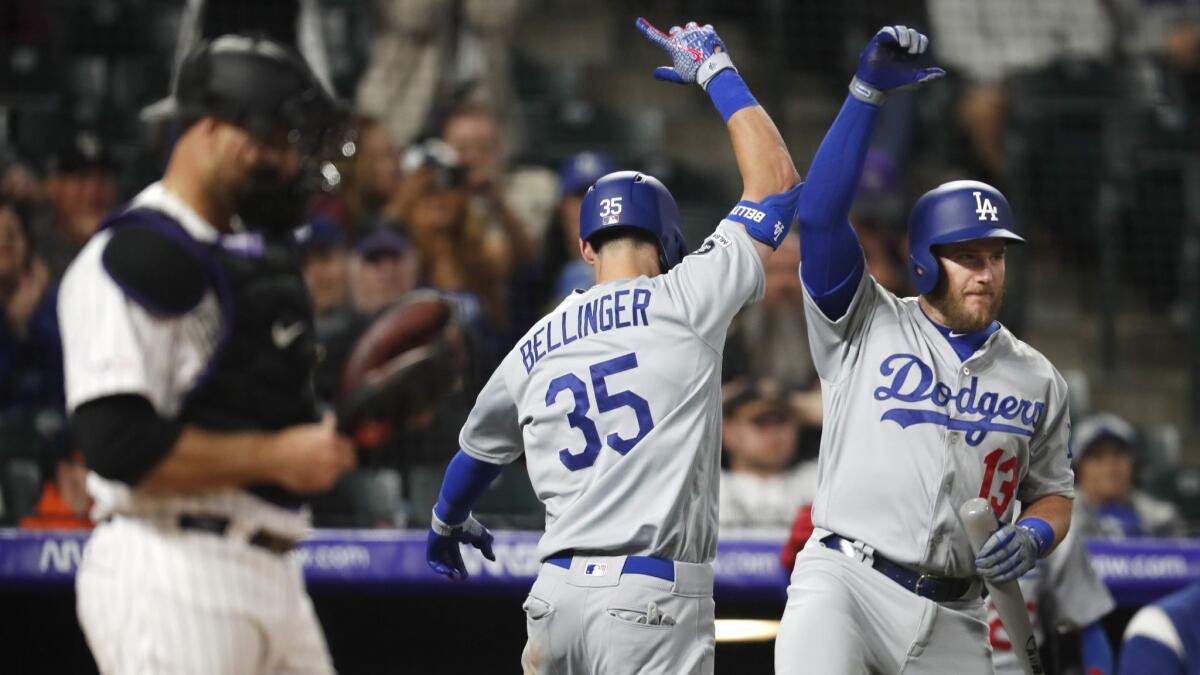 Dodgers' Cody Bellinger, center, celebrates hitting a solo home run with Max Muncy, right, as Colorado Rockies catcher Chris Iannetta stands in the foreground in the eighth inning.