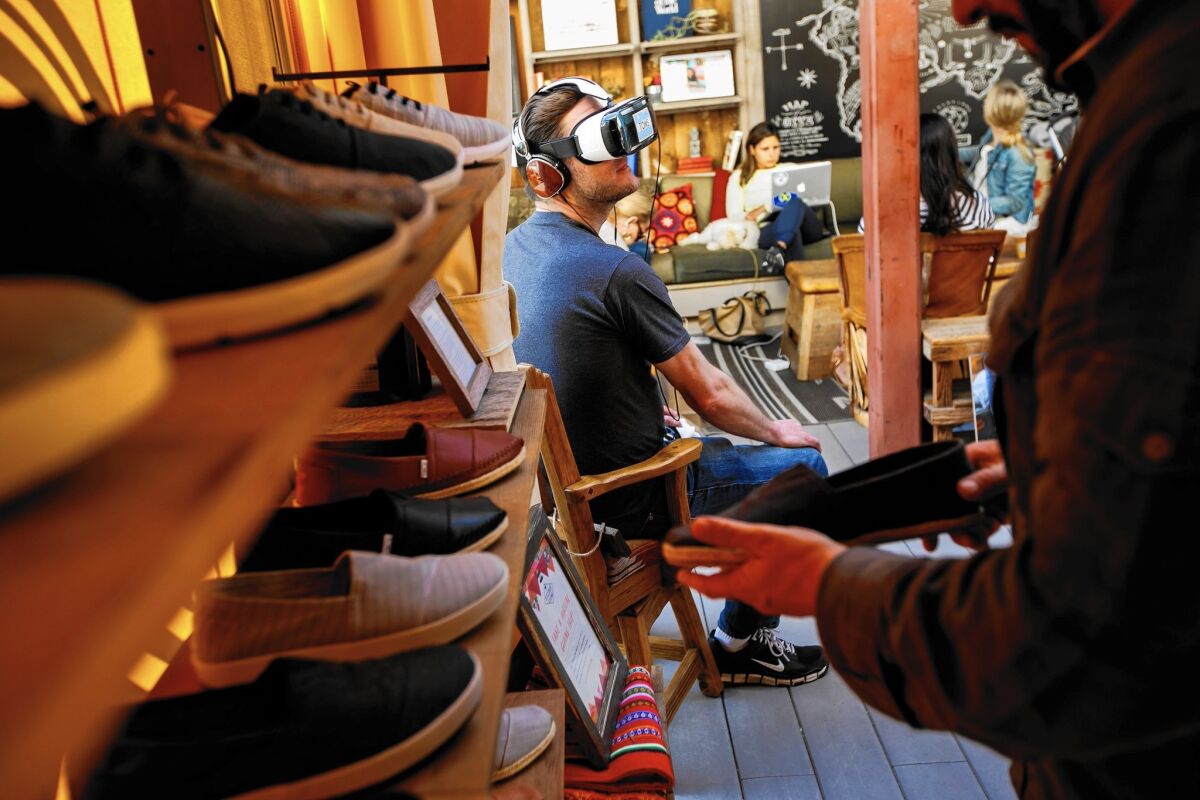 Brendon Moran, visiting from New York, tries out a virtual reality headset for the first time while his family shops at the Toms store on Abbot Kinney Boulevard in Venice.