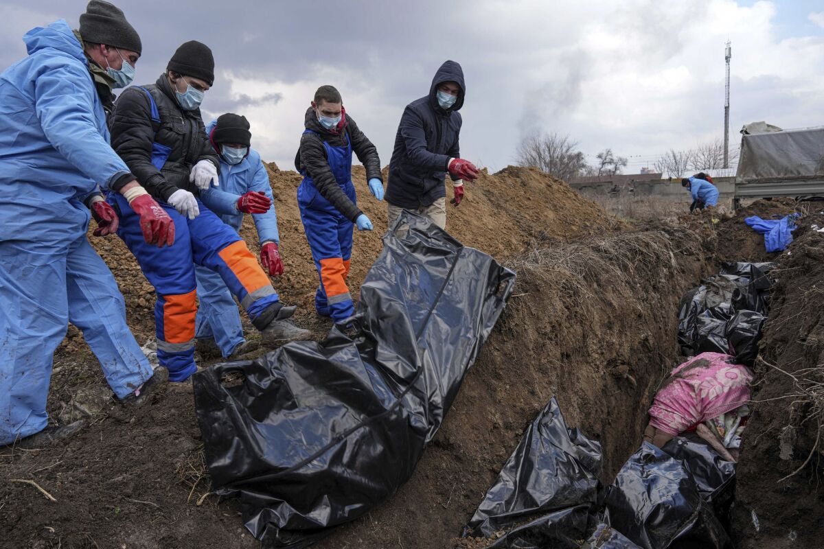 Dead bodies are placed into a mass grave on the outskirts of Mariupol, Ukraine, Wednesday, March 9, 2022 as people cannot bury their dead because of the heavy shelling by Russian forces. (AP Photo/Evgeniy Maloletka)