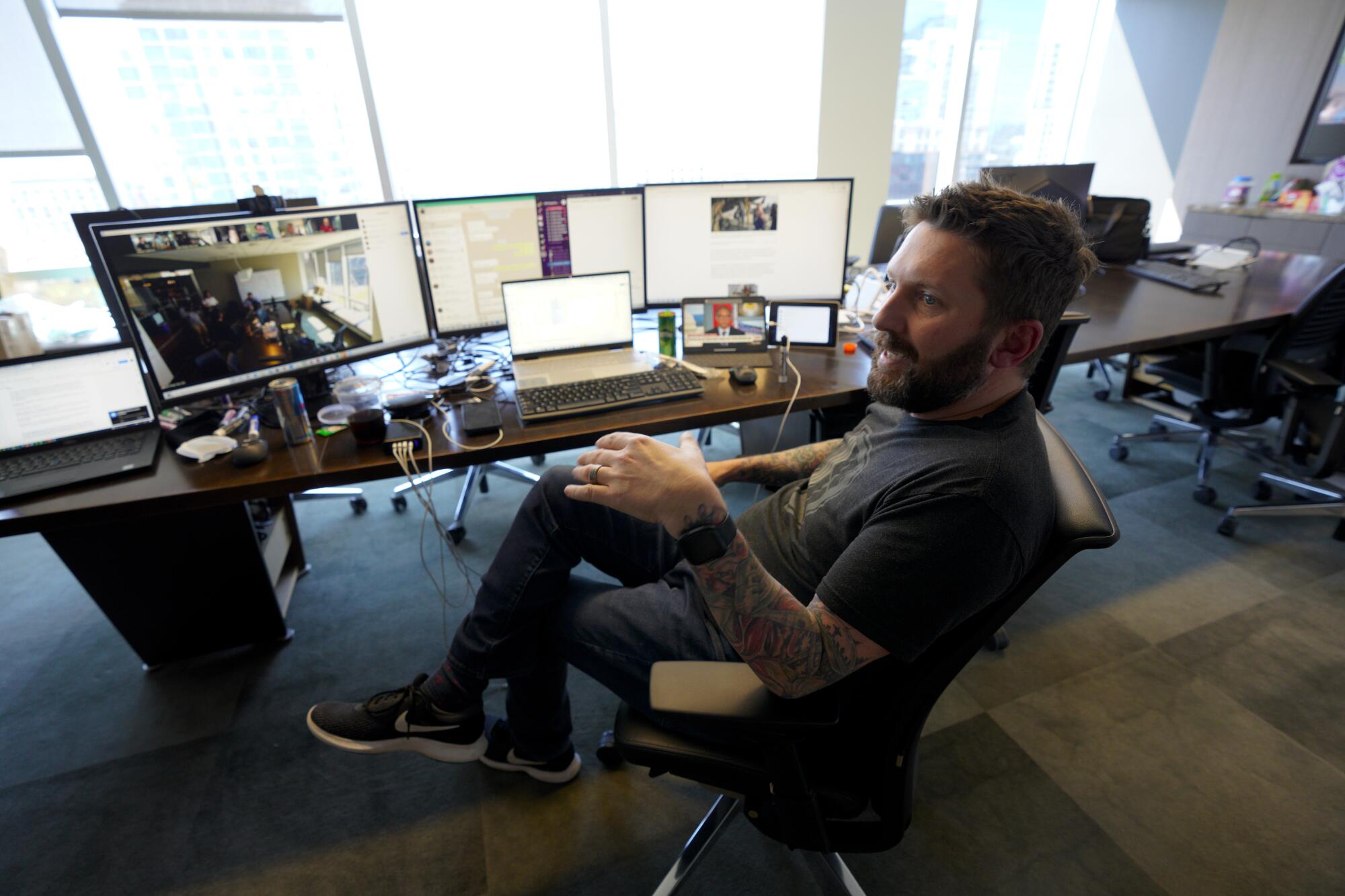 Navy veteran Shawn VanDiver sits at a desk with multiple computer screens.